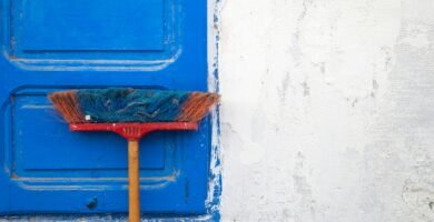 red and orange push boroom leaned on blue door